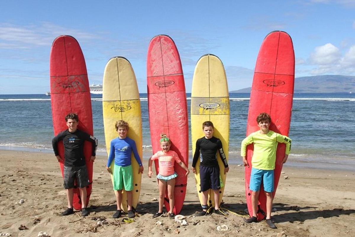 Un grupo de personas de pie frente a tablas de surf en la playa.