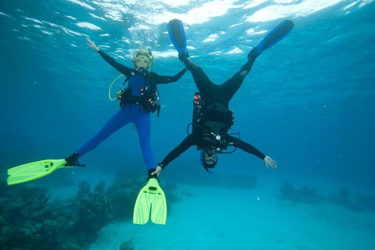Dos personas están paradas en el océano con sus manos en el agua.