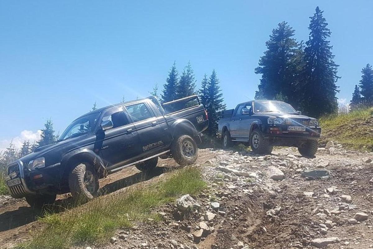 two trucks are parked on a dirt road