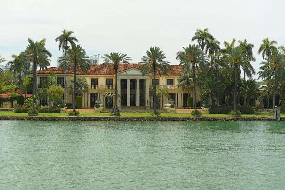 una grande casa con palme di fronte a uno specchio d'acqua