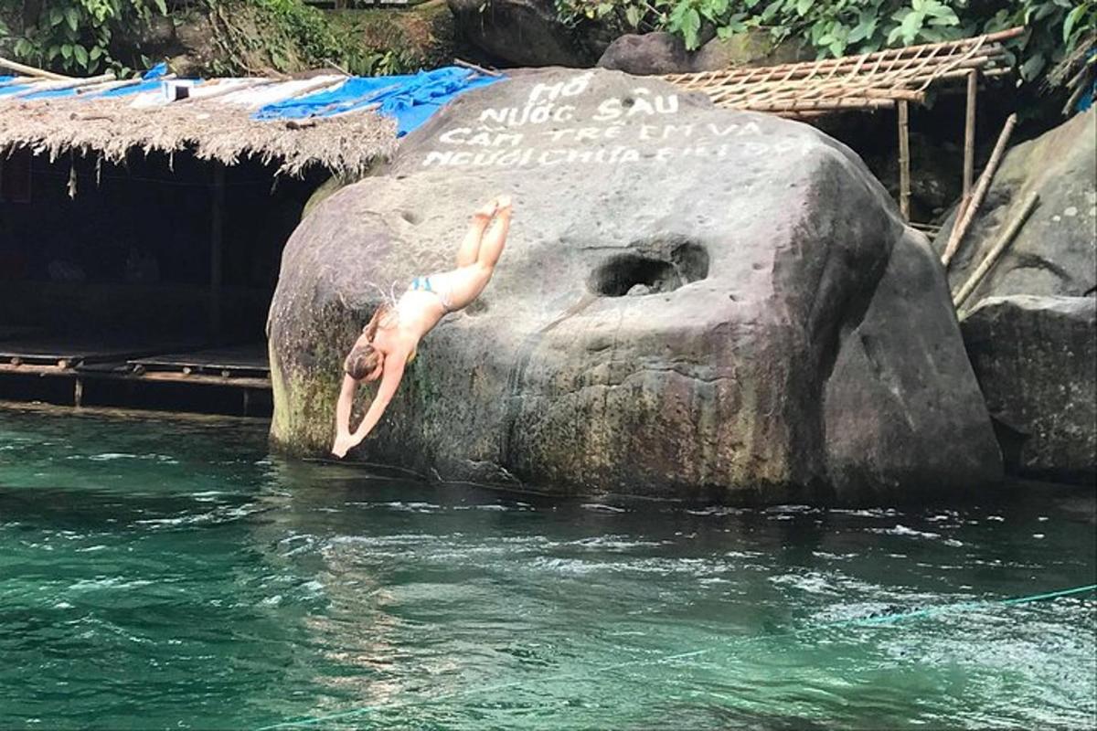 uma pessoa pulando de uma pedra na água
