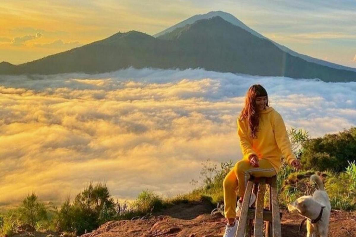 a woman sitting on a stool on a mountain with a dog