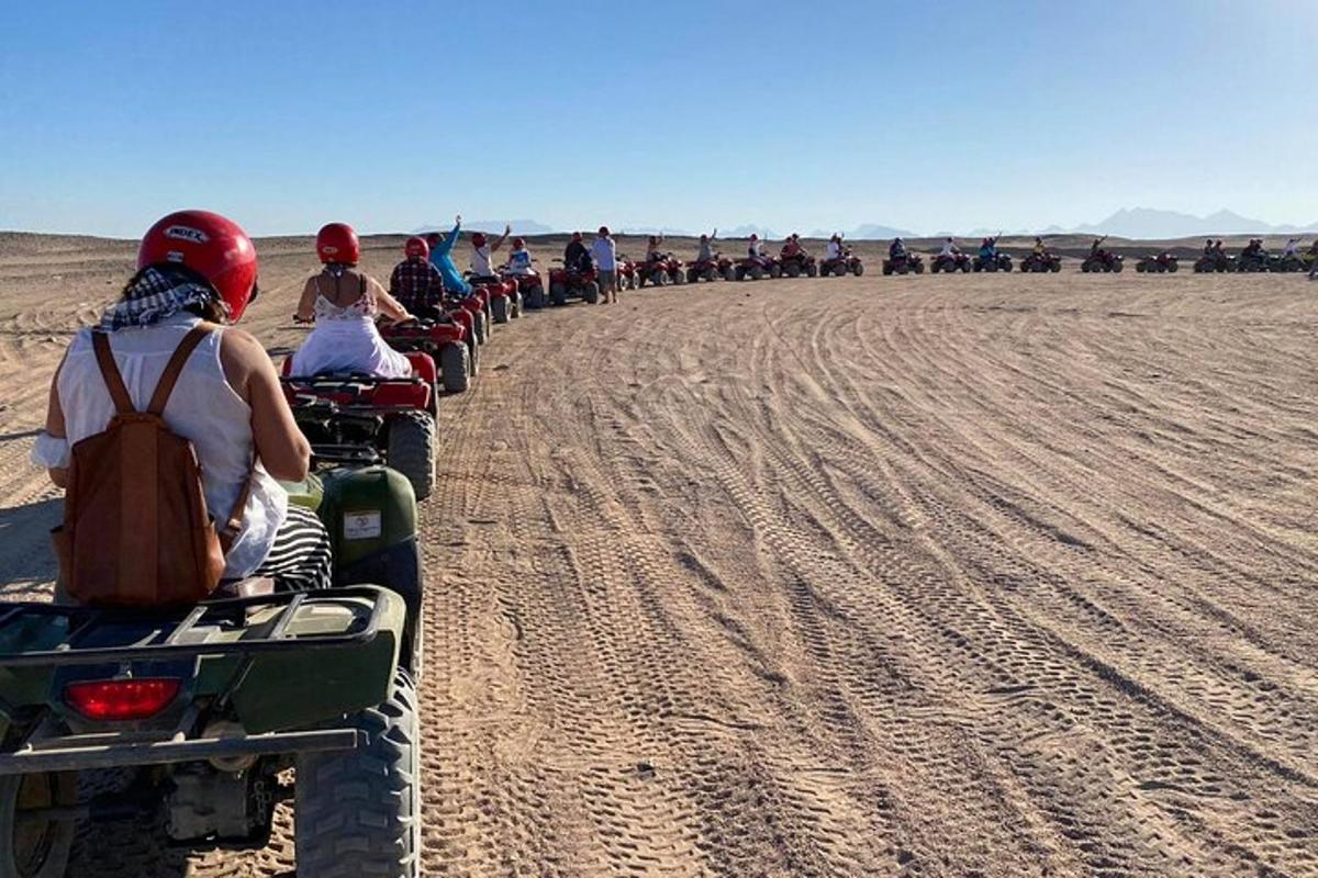 a group of people riding on quad bikes in the desert