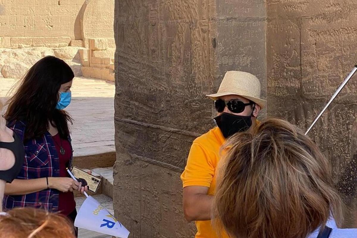 Ένας άντρας με μάσκα στέκεται δίπλα σε μια ομάδα ανθρώπων