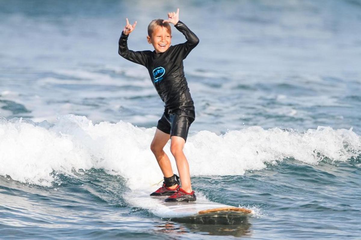 en ung gutt som rir på en bølge på et surfebrett i havet