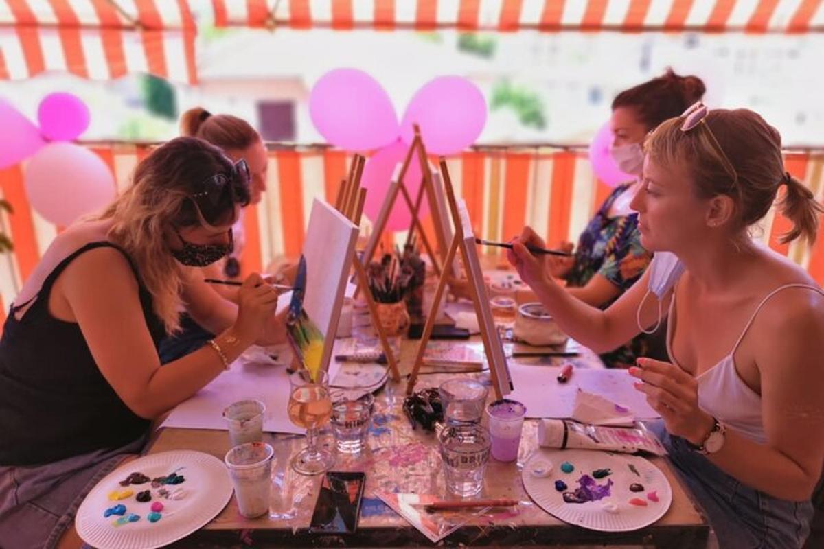 eine Gruppe von Frauen, die mit Gemälden an einem Tisch sitzen