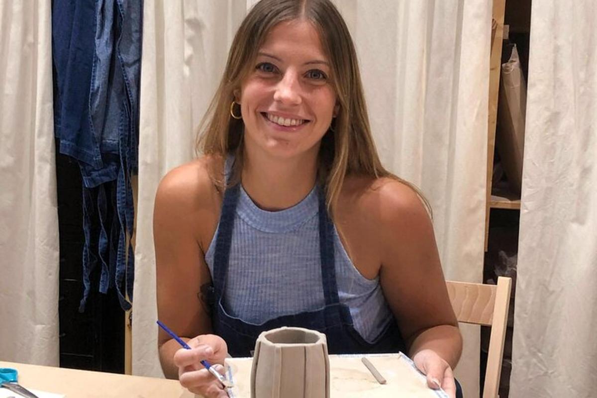 Una mujer sentada en una mesa sosteniendo un bolígrafo y sonriendo.