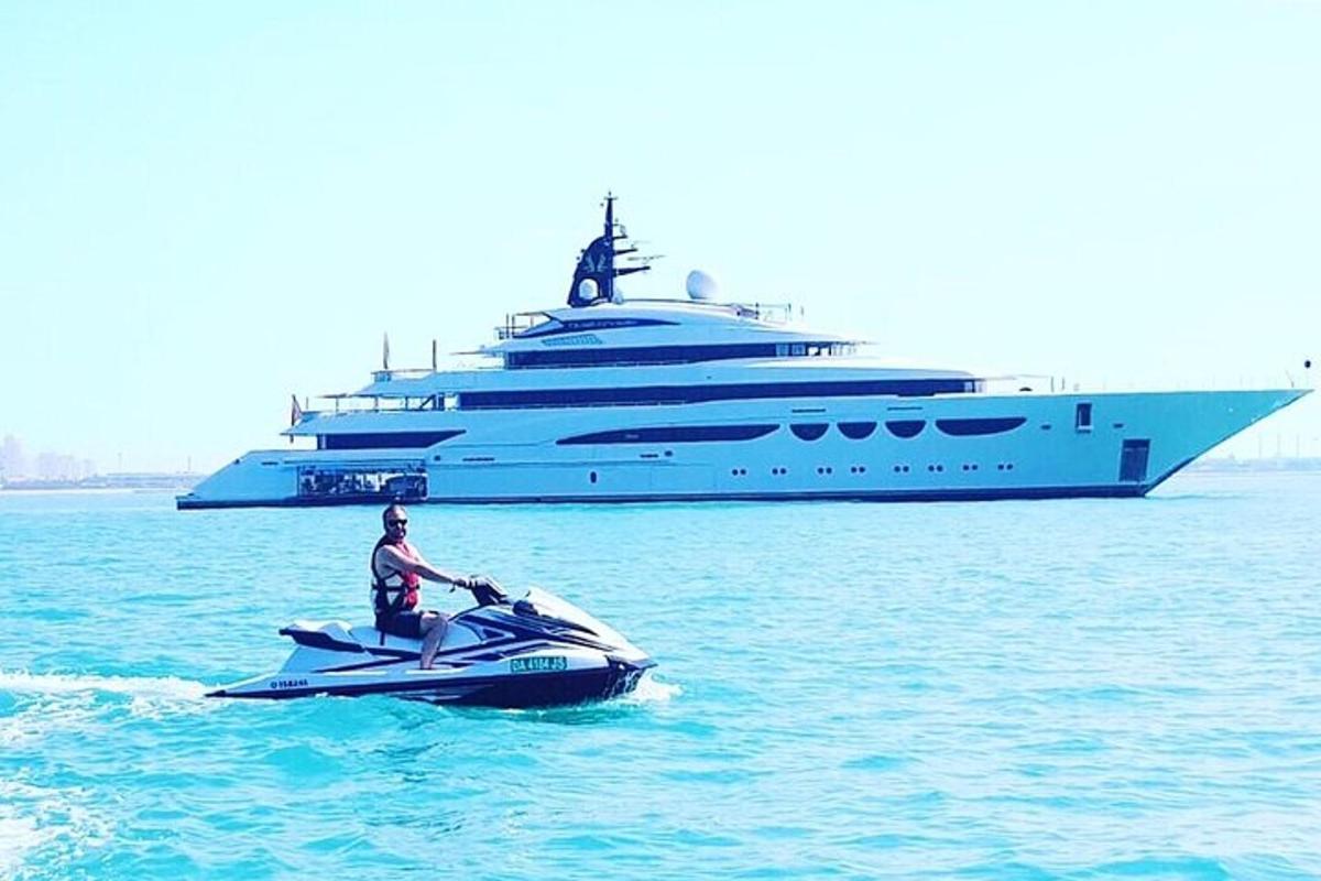 a man riding a jet ski in front of a large yacht