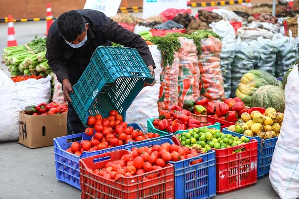 muž držící košík s ovocem a zeleninou na trhu