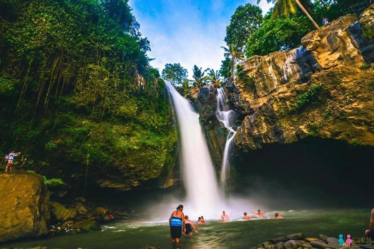 um grupo de pessoas em pé em frente a uma cachoeira