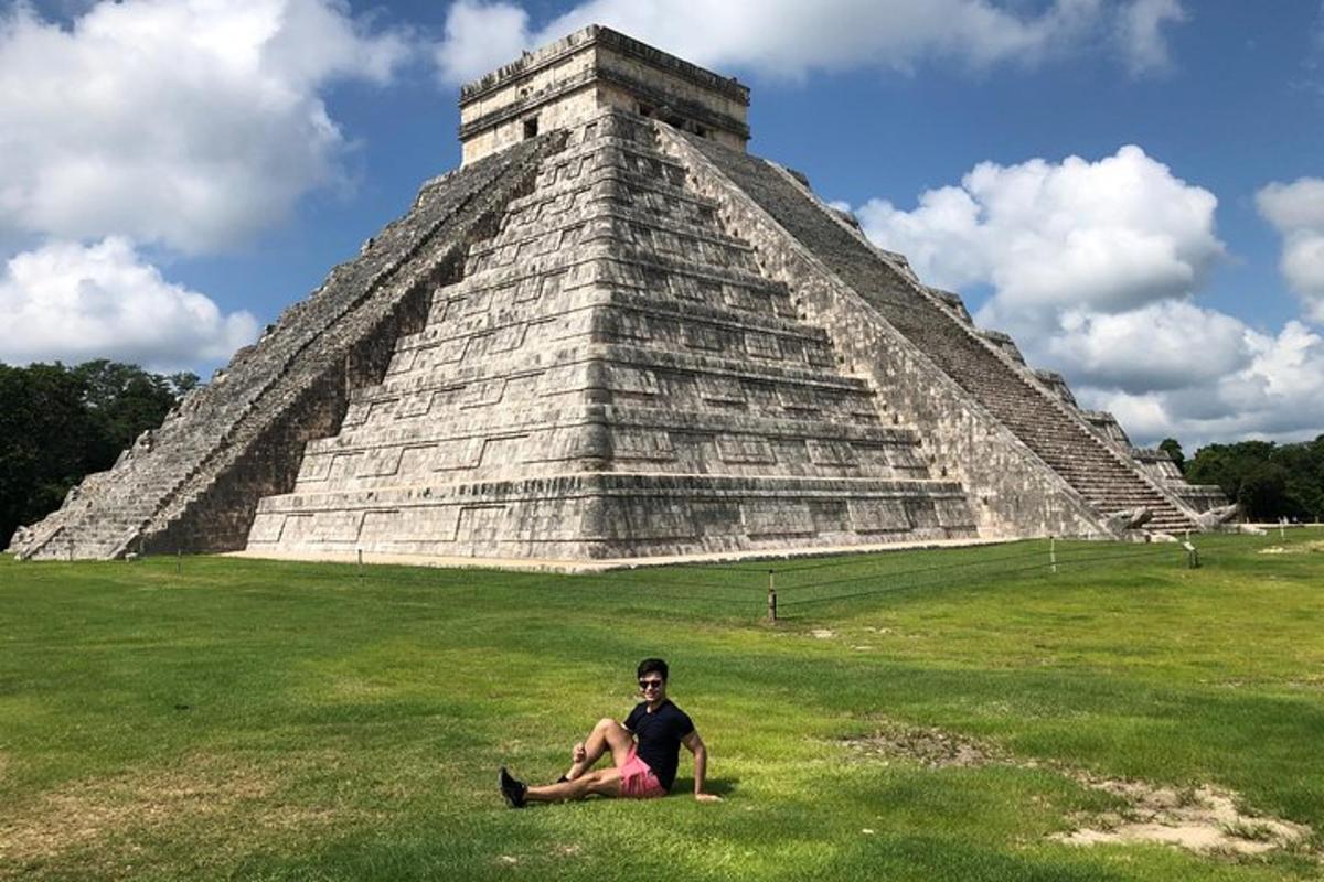muž sedící na trávě před pyramidou