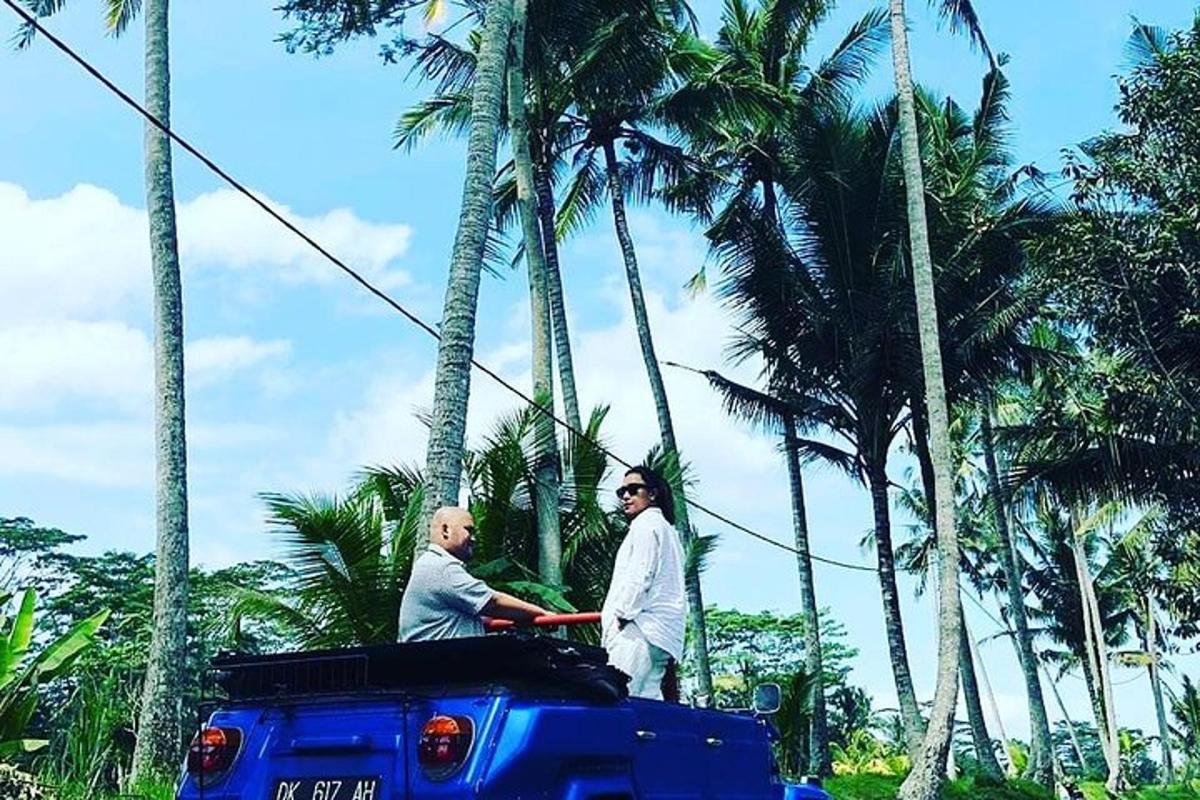 two men standing on the back of a blue truck with palm trees