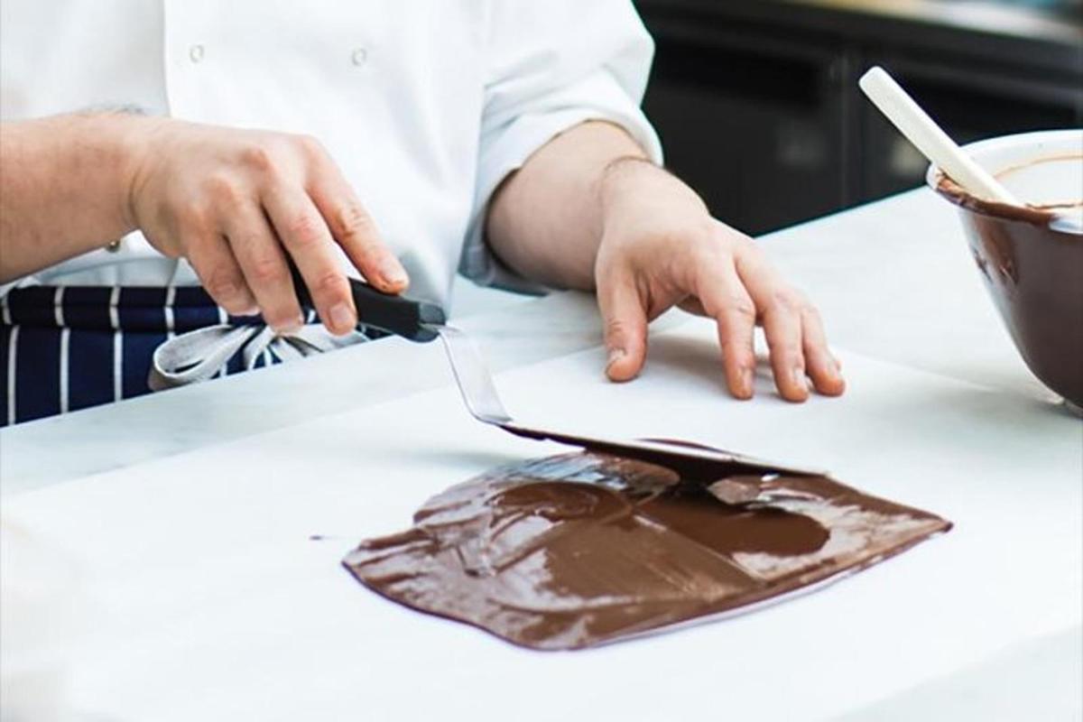 una persona che taglia un pezzo di cioccolato su un bancone