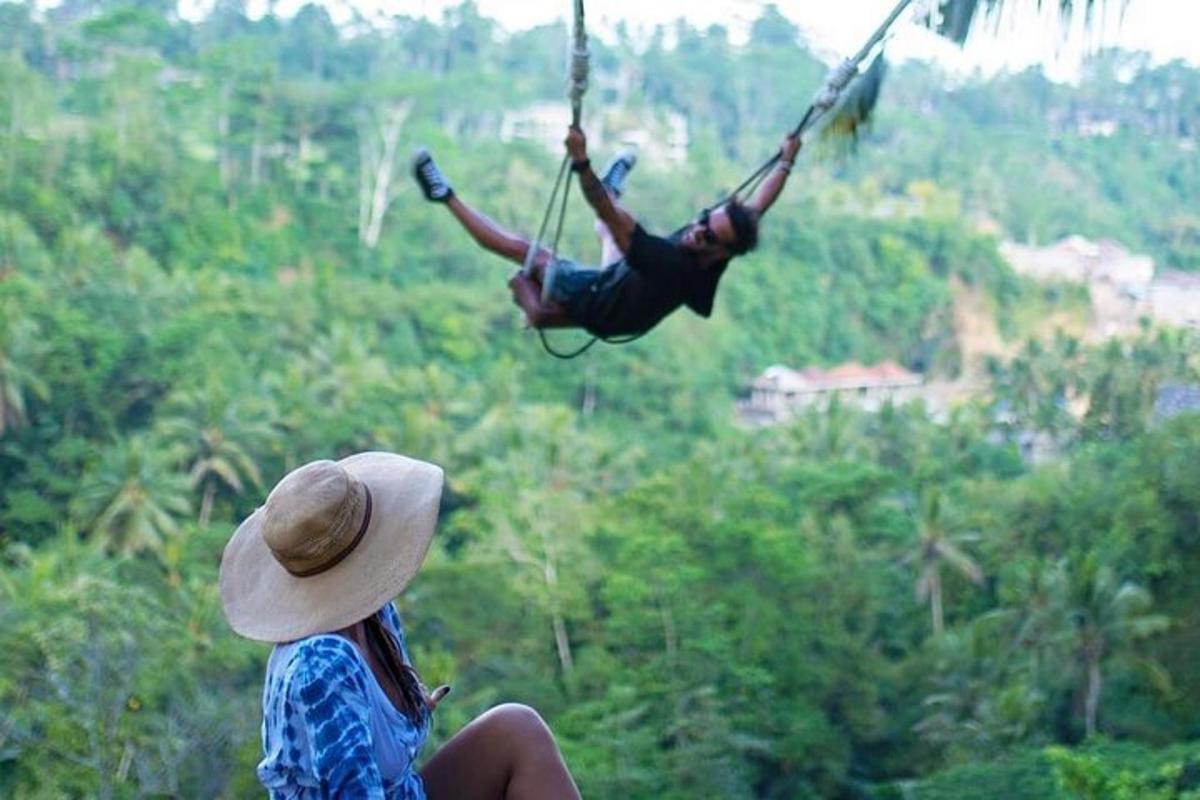 ang isang babae ay nanonood ng isang lalaki sa isang lubid swing