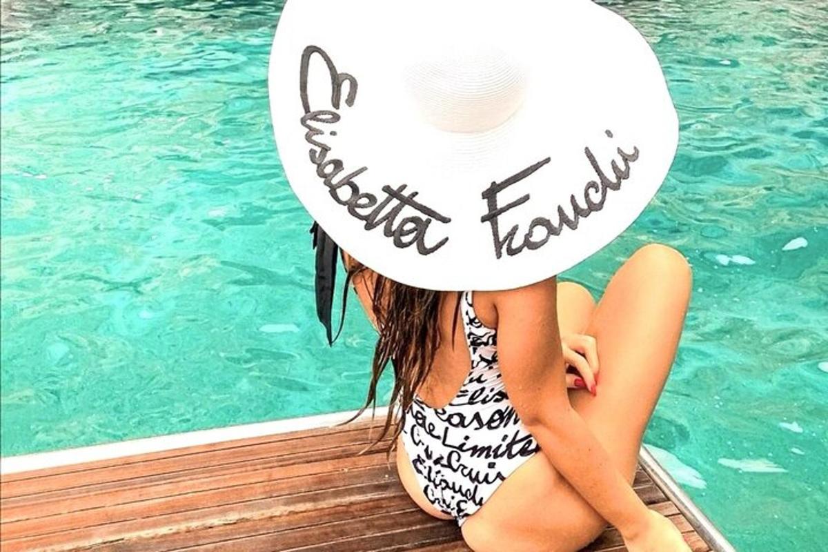 Una niña sentada en un muelle junto a una piscina.