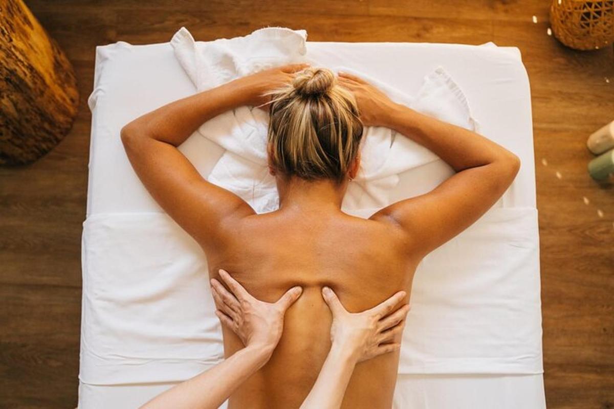 žena bez trička ležící na posteli s rukama na zádech