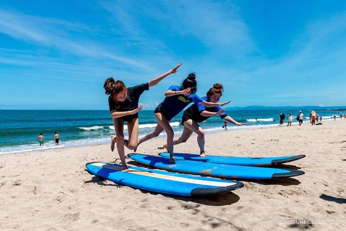 Tres chicas saltando sobre tablas de surf en la playa
