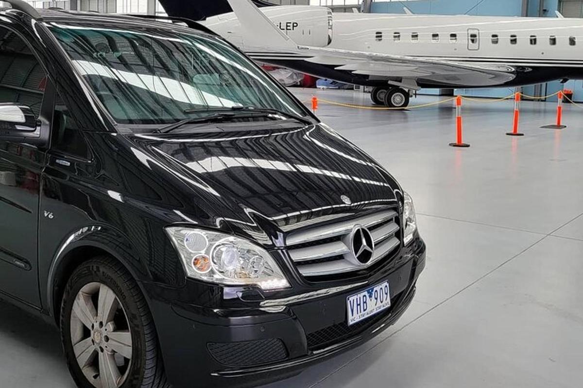 un furgone nero parcheggiato in un hangar accanto a un aereo