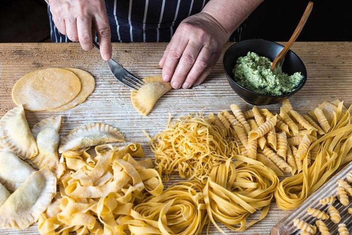 een persoon die pasta en dipsaus op een snijplank klaarmaakt