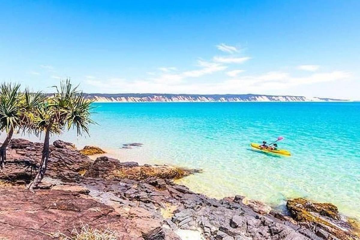 a yellow boat in the water next to a beach