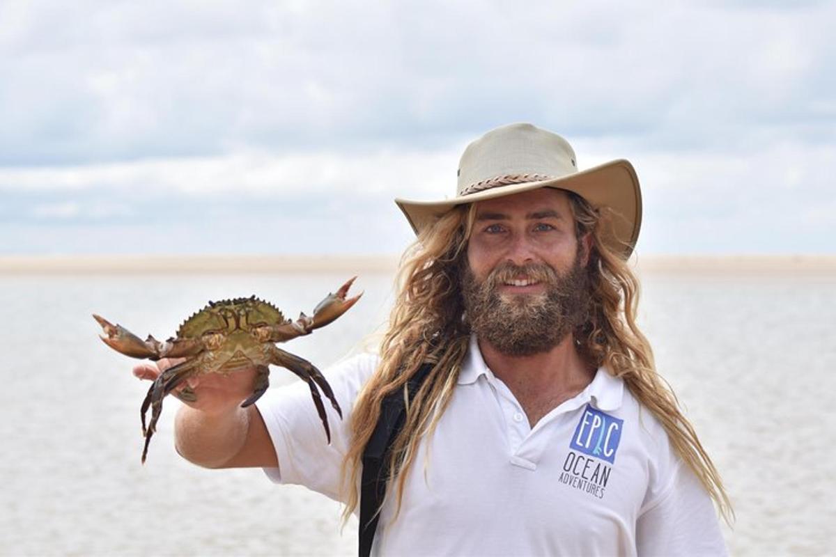 a man wearing a cowboy hat holding a crab