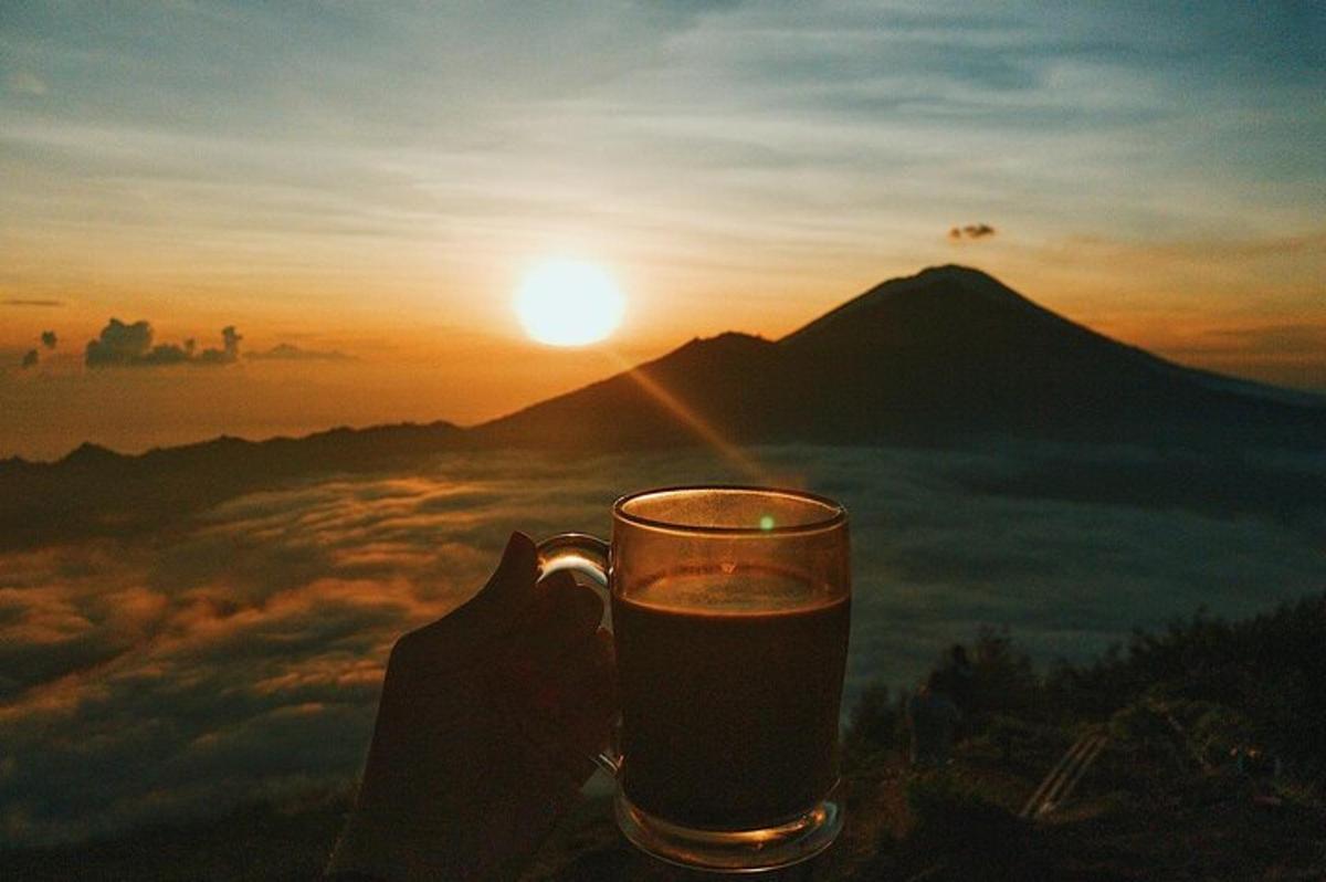 una persona sosteniendo un vaso de cerveza frente a una montaña
