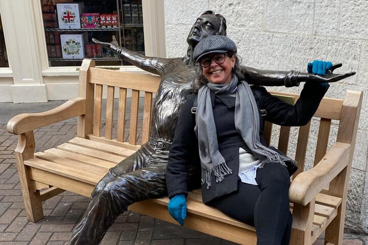 una mujer sentada en un banco junto a una estatua