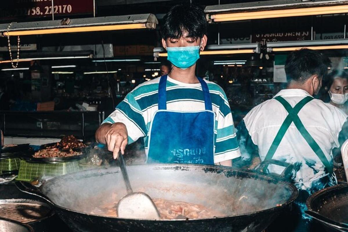 un home cuinant menjar en una paella a la cuina