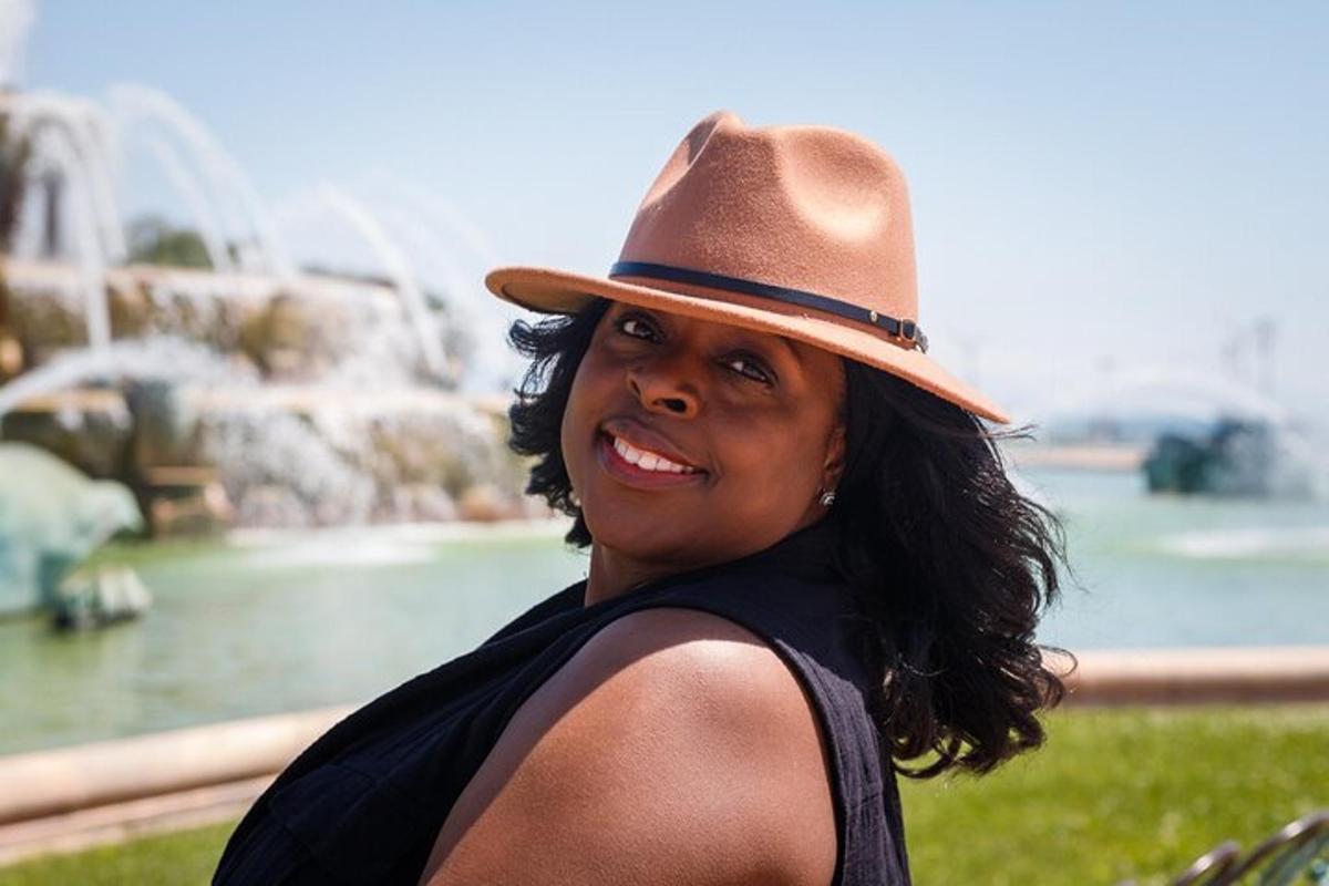 a woman wearing a hat standing in front of a fountain