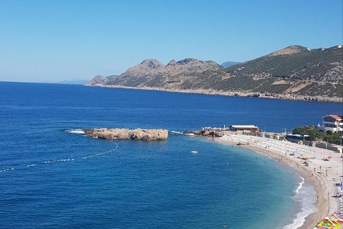 плажа са камењем у води и људима на њој