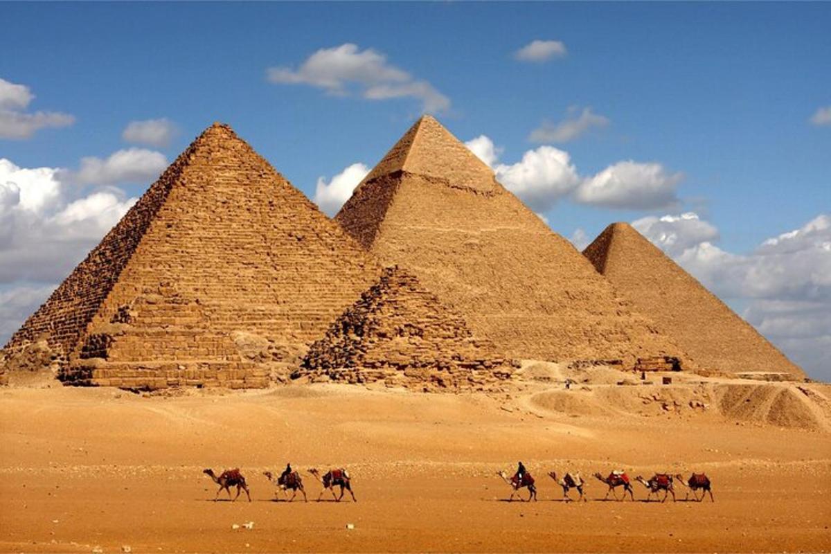 Skupina lidí na koních před pyramidami