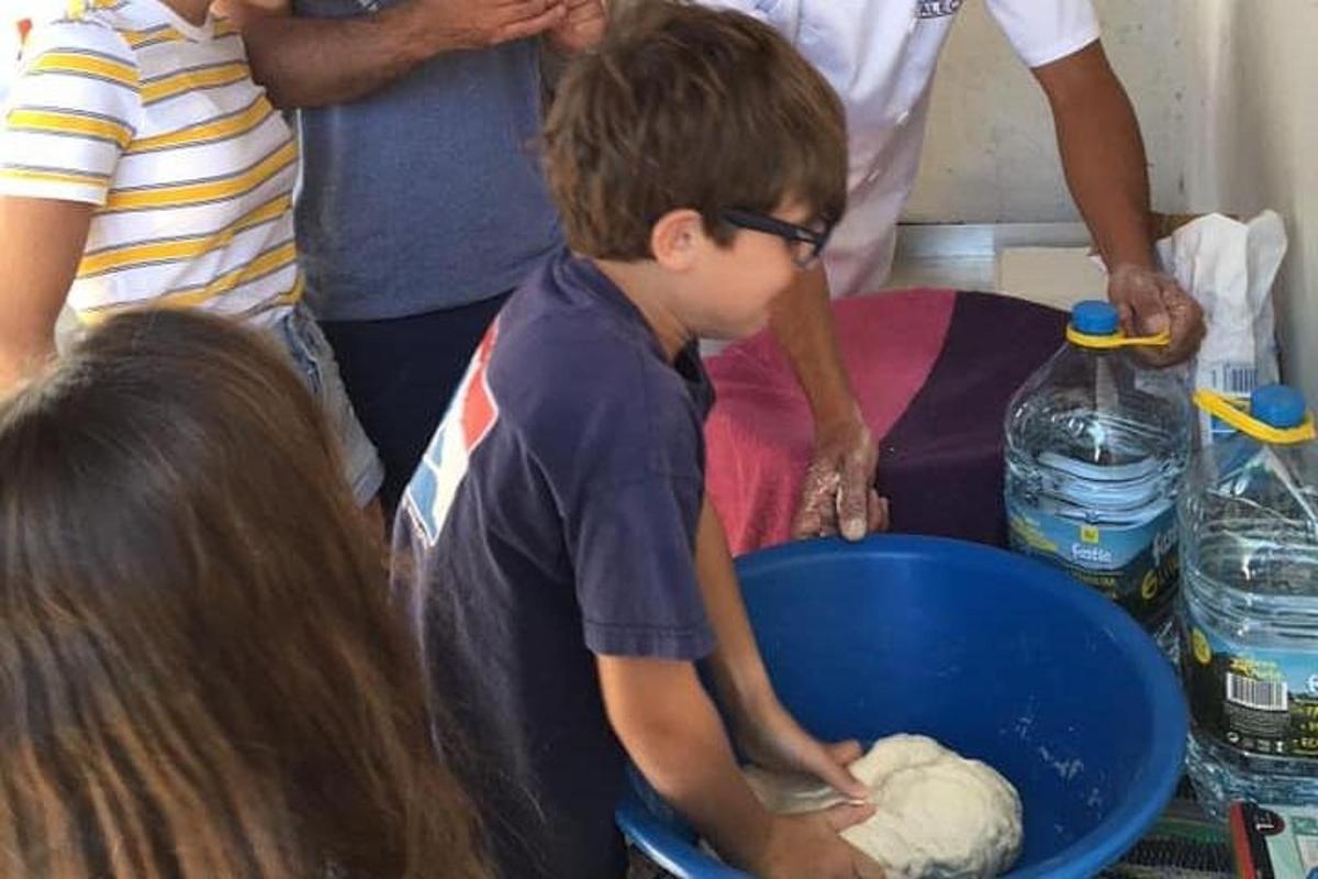 a young boy mixing dough in a blue bowl