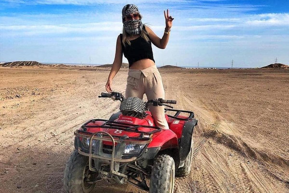 seorang wanita berdiri di atas basikal quad di padang pasir