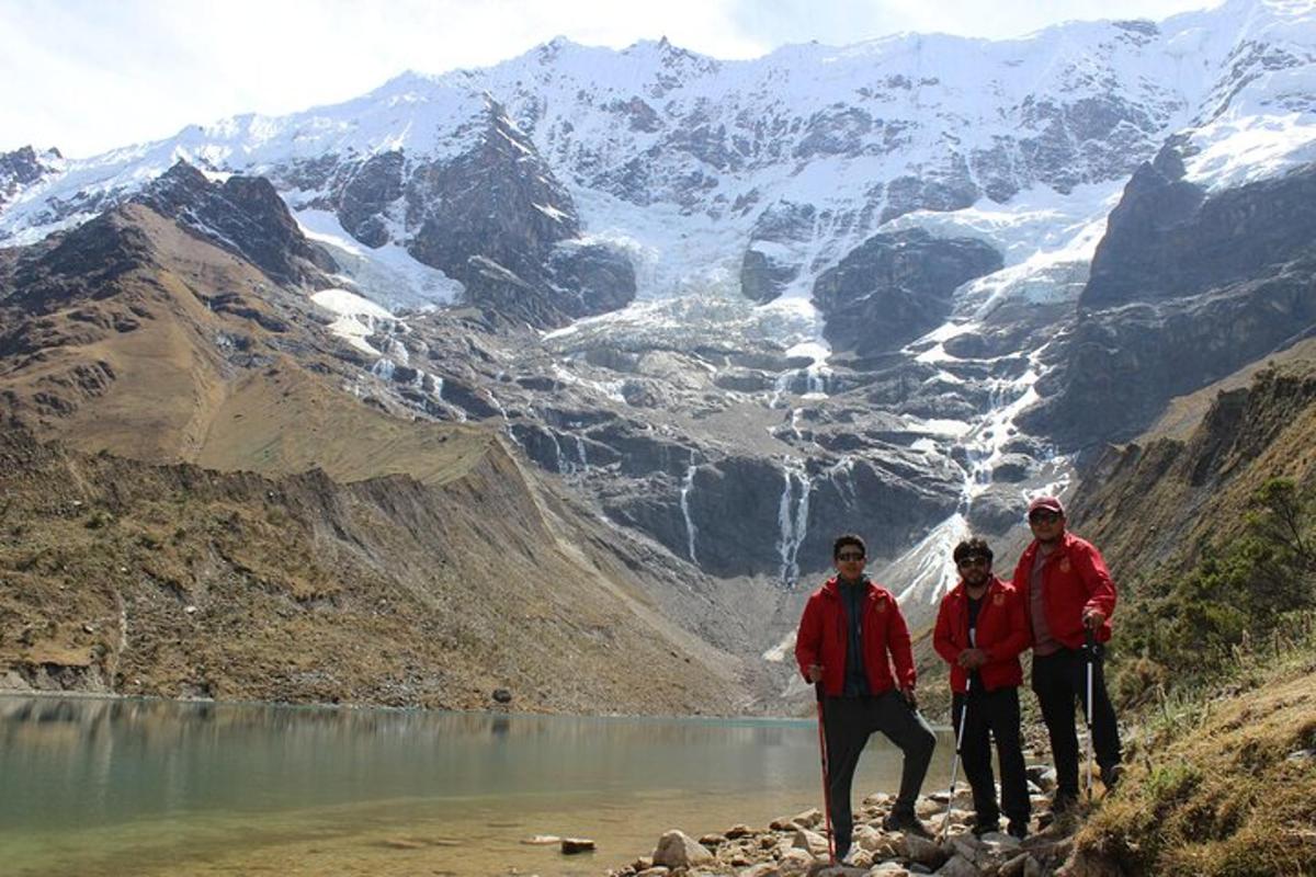 Un grupo de tres hombres de pie frente a una montaña.