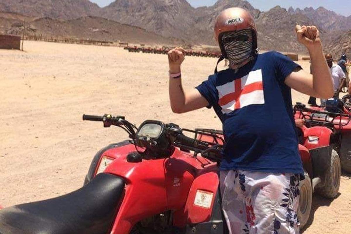 eine Person, die neben einem Motorrad in der Wüste steht