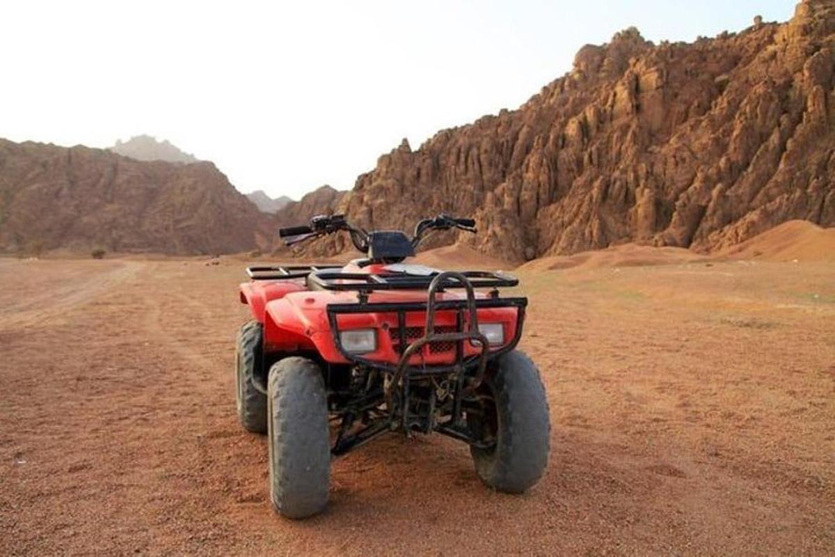 egy piros ATV parkolt a sivatag közepén