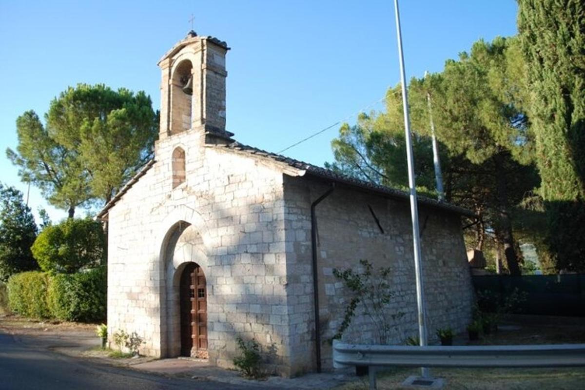 Una pequeña iglesia de piedra con una torre de reloj en una calle