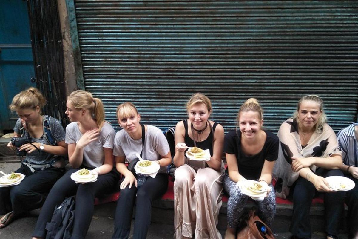 a group of women sitting on a bench eating food