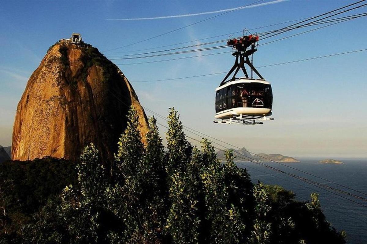 a cable car flying over a mountain with a rock