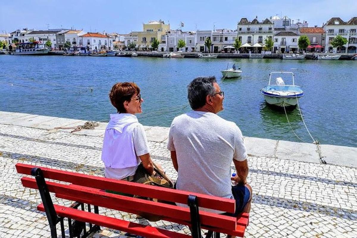 δύο άτομα κάθονται σε ένα παγκάκι δίπλα στο νερό