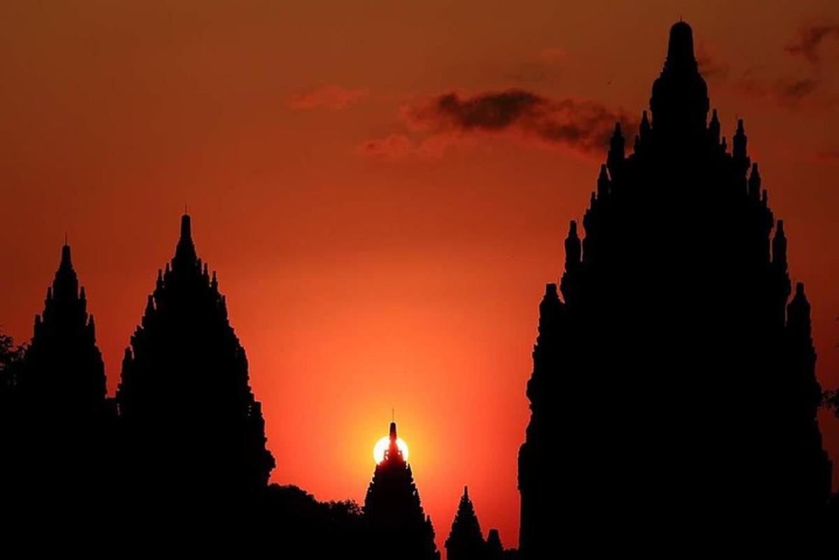 uma silhueta de um templo com um pôr do sol ao fundo