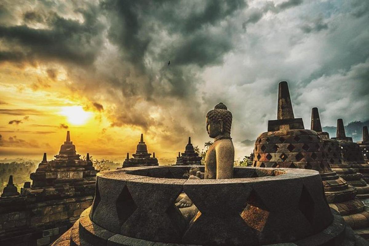 une statue devant un temple avec le coucher du soleil
