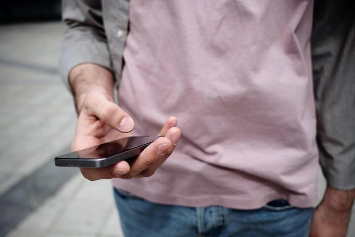muž držící v ruce mobilní telefon