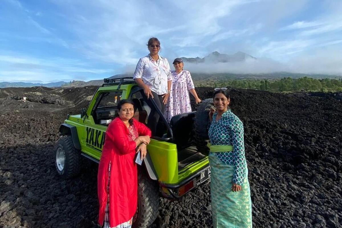 a group of women standing next to a green jeep