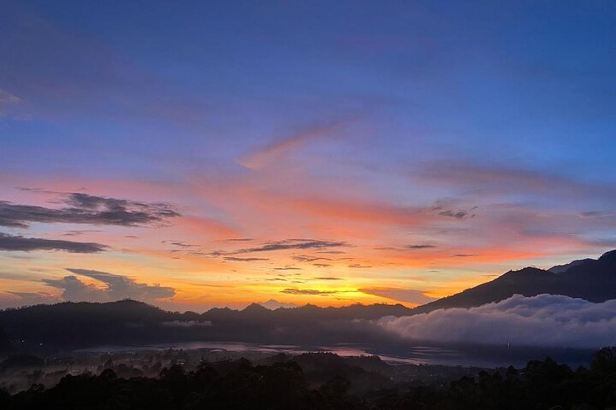 a view of a sunset with clouds and mountains