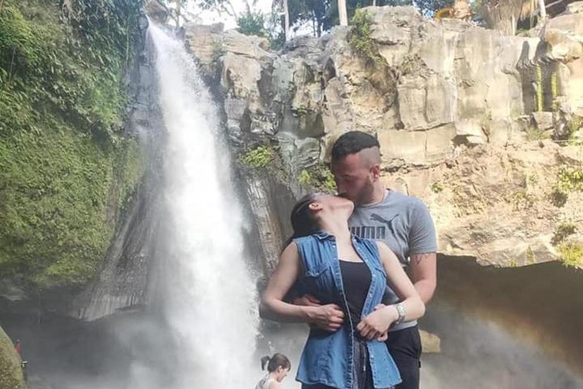 um homem e uma mulher em pé em frente a uma cachoeira