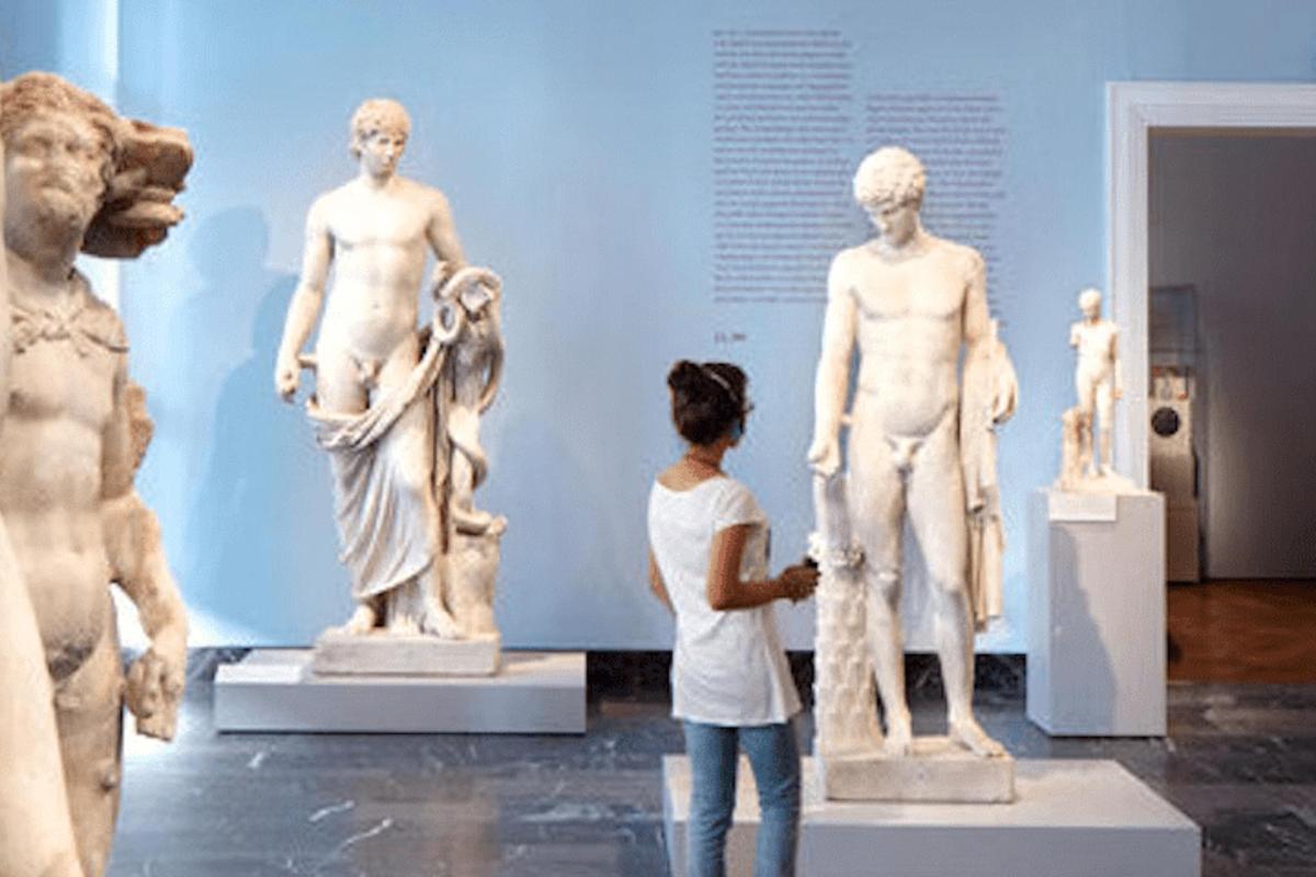 a woman looking at statues in a museum