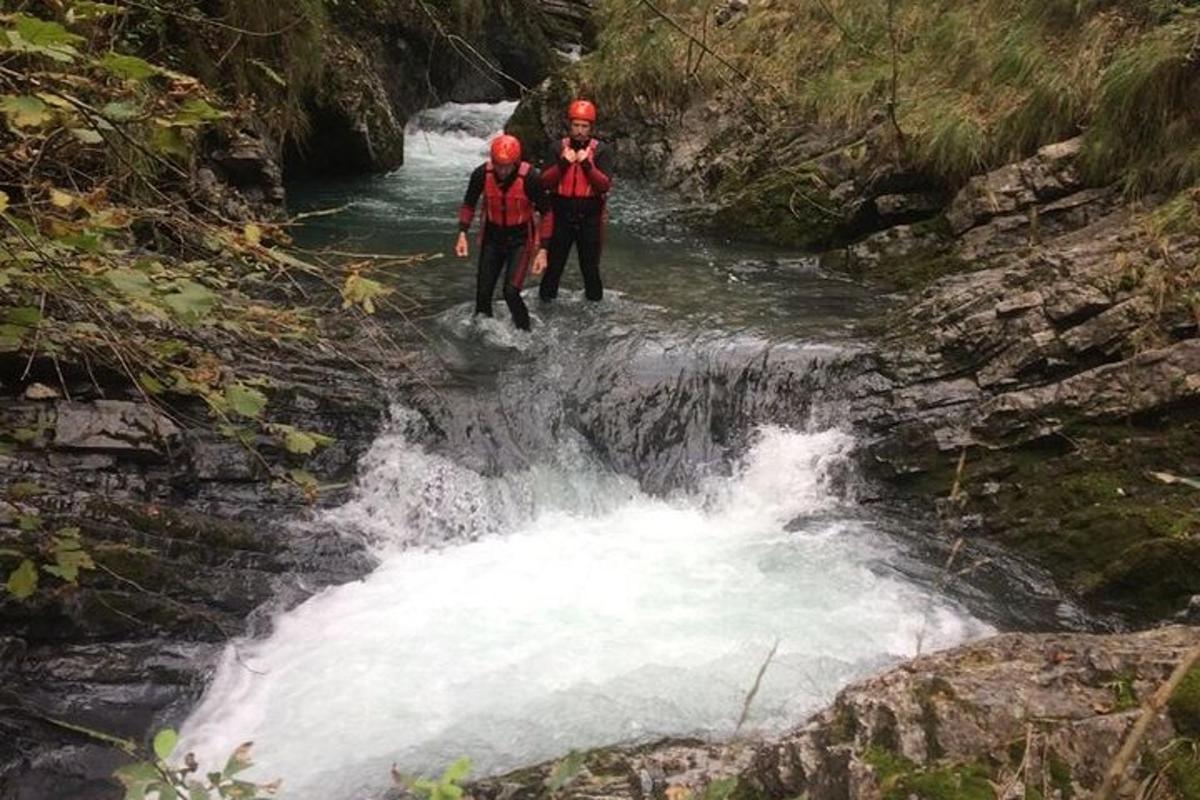 zwei Menschen gehen durch einen Wasserfall in einem Fluss