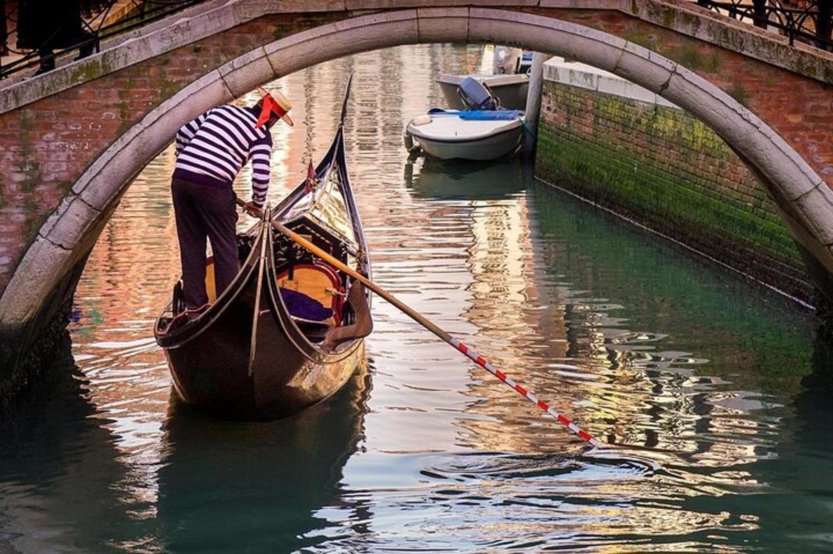 seorang lelaki sedang mendayung gondola di bawah jambatan