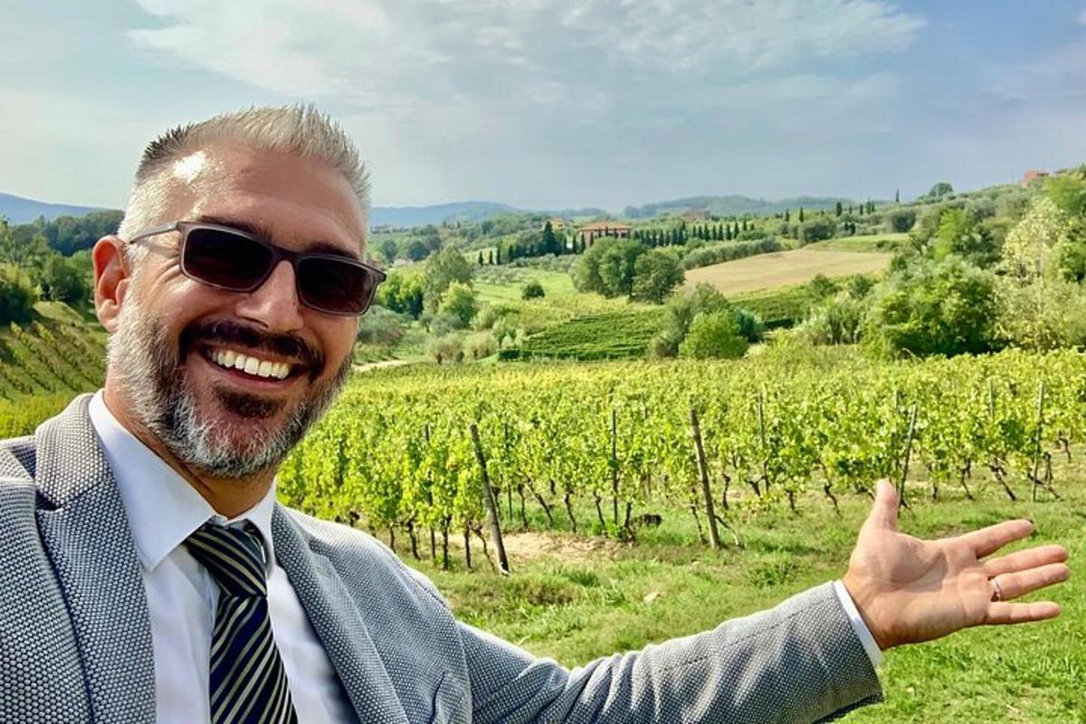 un uomo in giacca e occhiali da sole che indica un vigneto